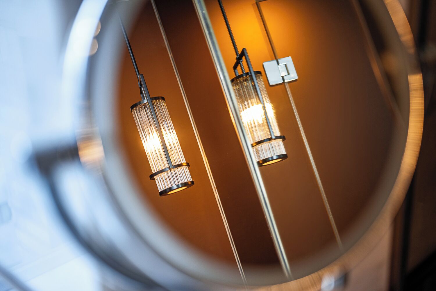 Two hanging pendant lights with a warm glow, suspended from a ceiling with a circular design.