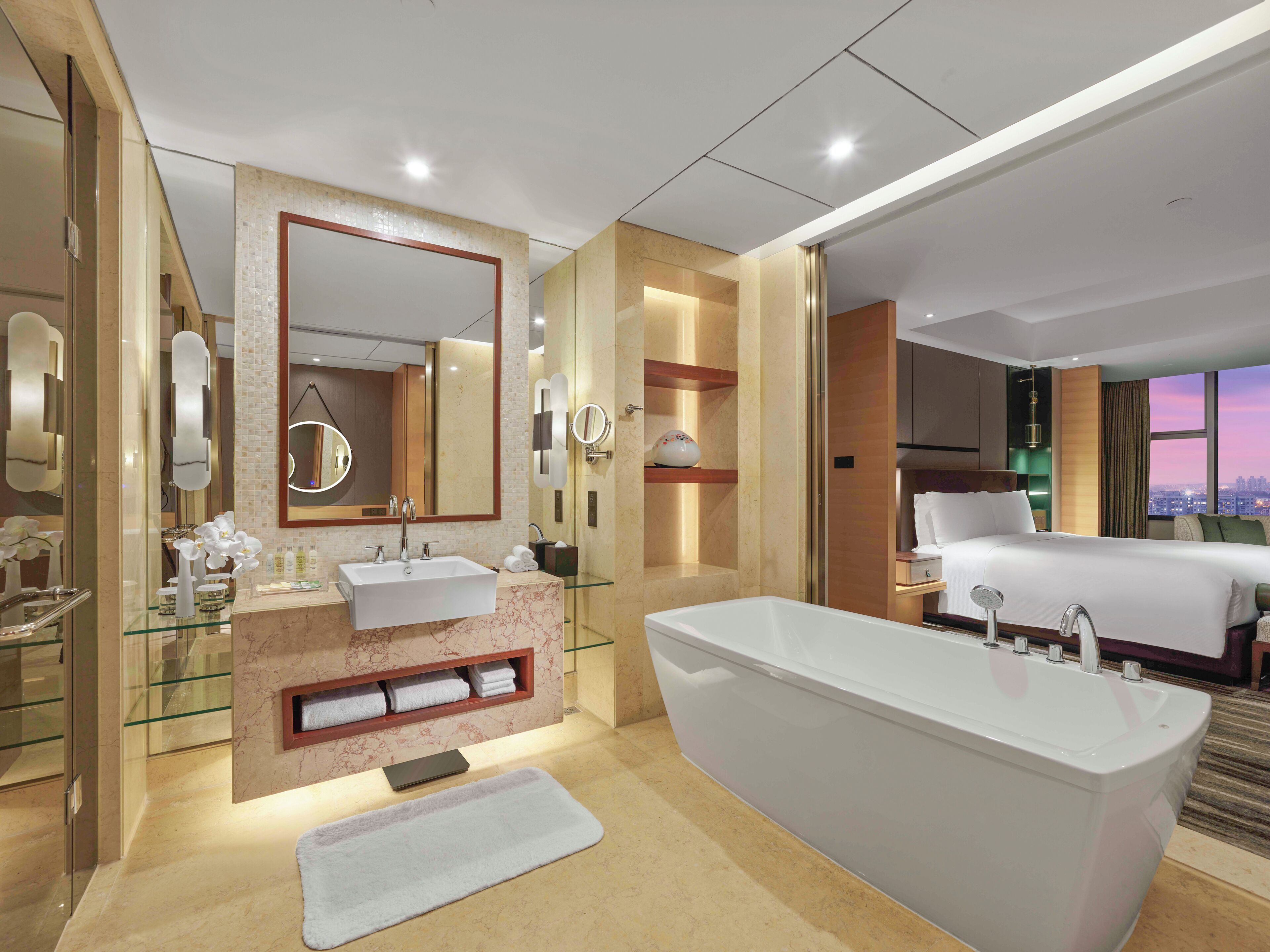 Ein modernes Badezimmer in einem Hotel mit einer großen Badewanne, einem Glastisch für die Toilette und einem großen Spiegel.