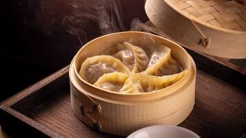 A bamboo steamer with dumplings on a wooden tray.