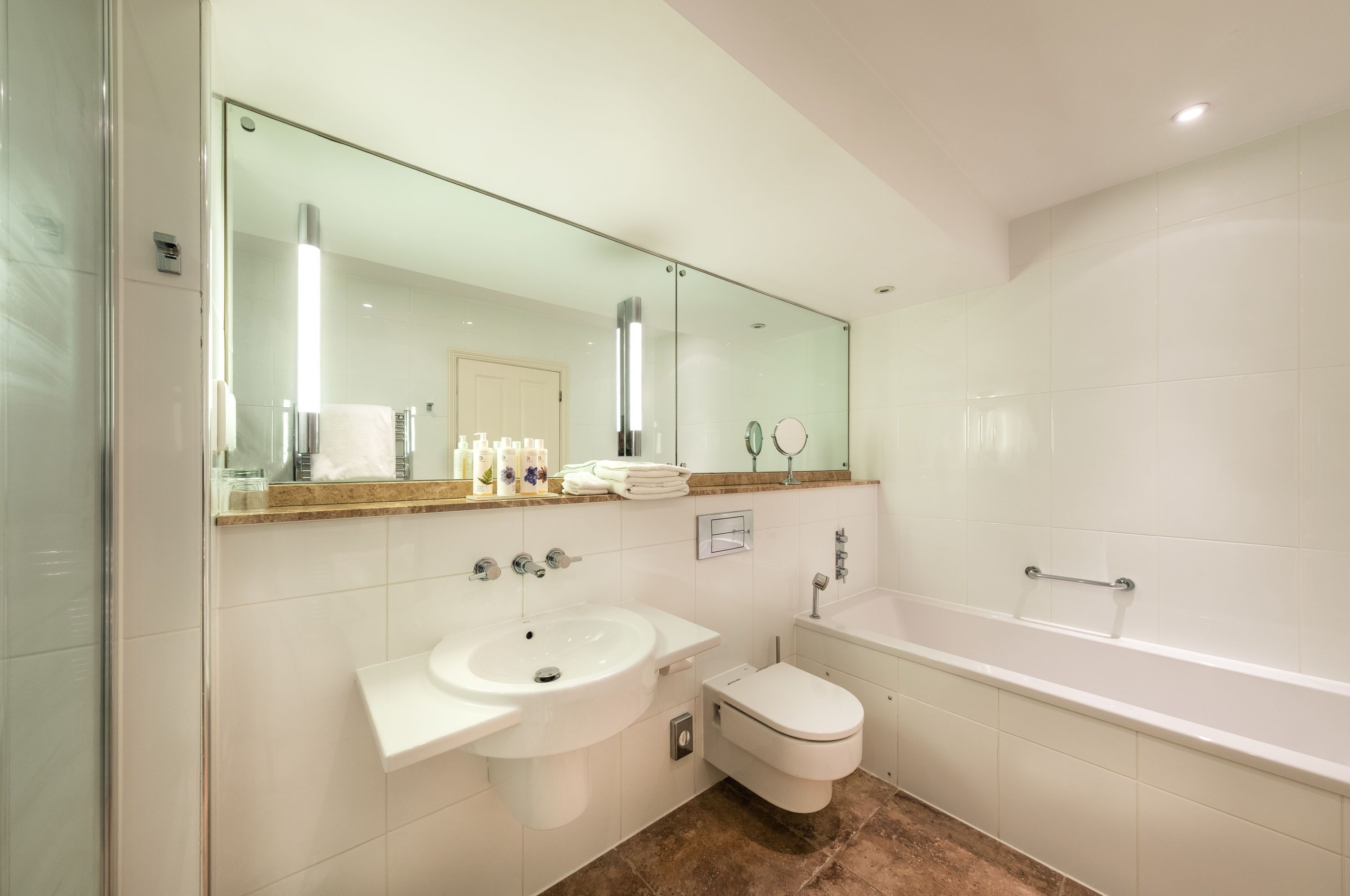 Een moderne badkamer met een douchecabine van glas, een wit wastafelmeubel, een toilet en een bad.