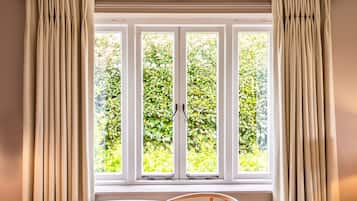 A room with a large window, curtains, and a chair.