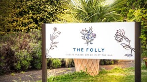 Een bordje voor 'The Folly' met de melding voor gasten om in te checken bij de bar.