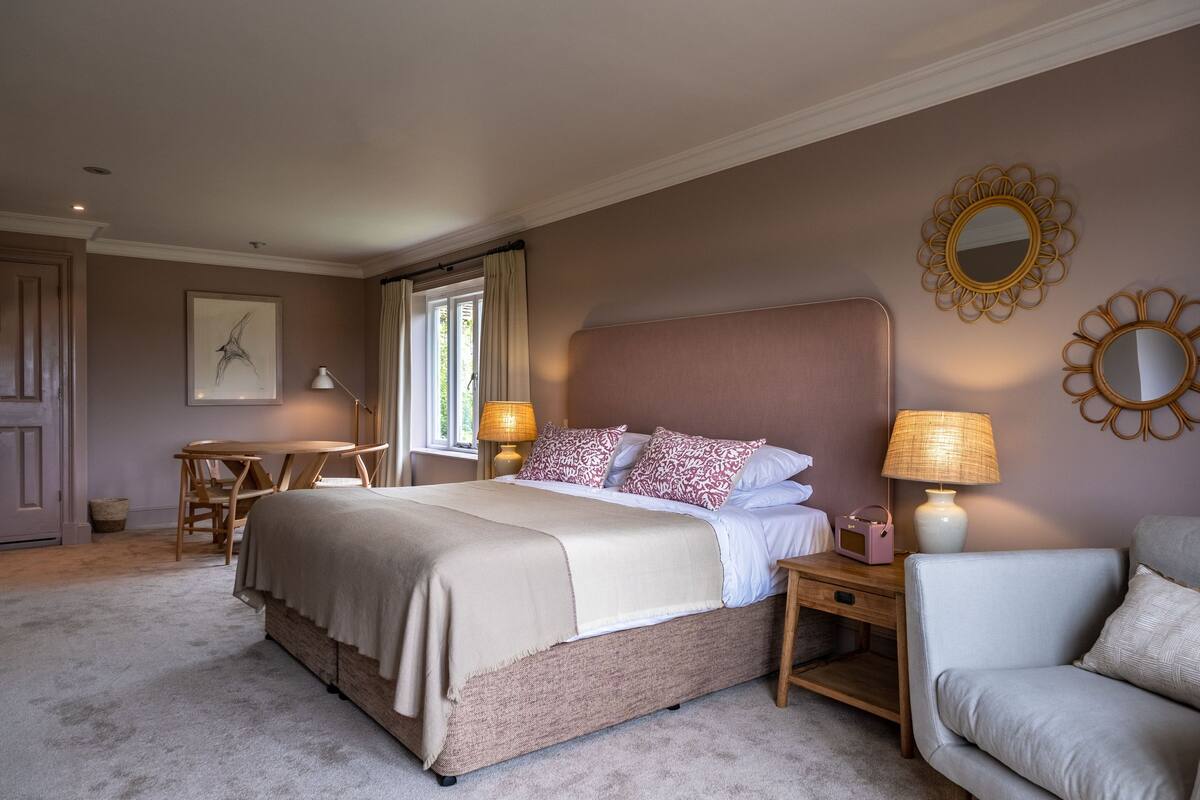 Een slaapkamer met een groot bed, nachtkastjes, een stoel en een bank.