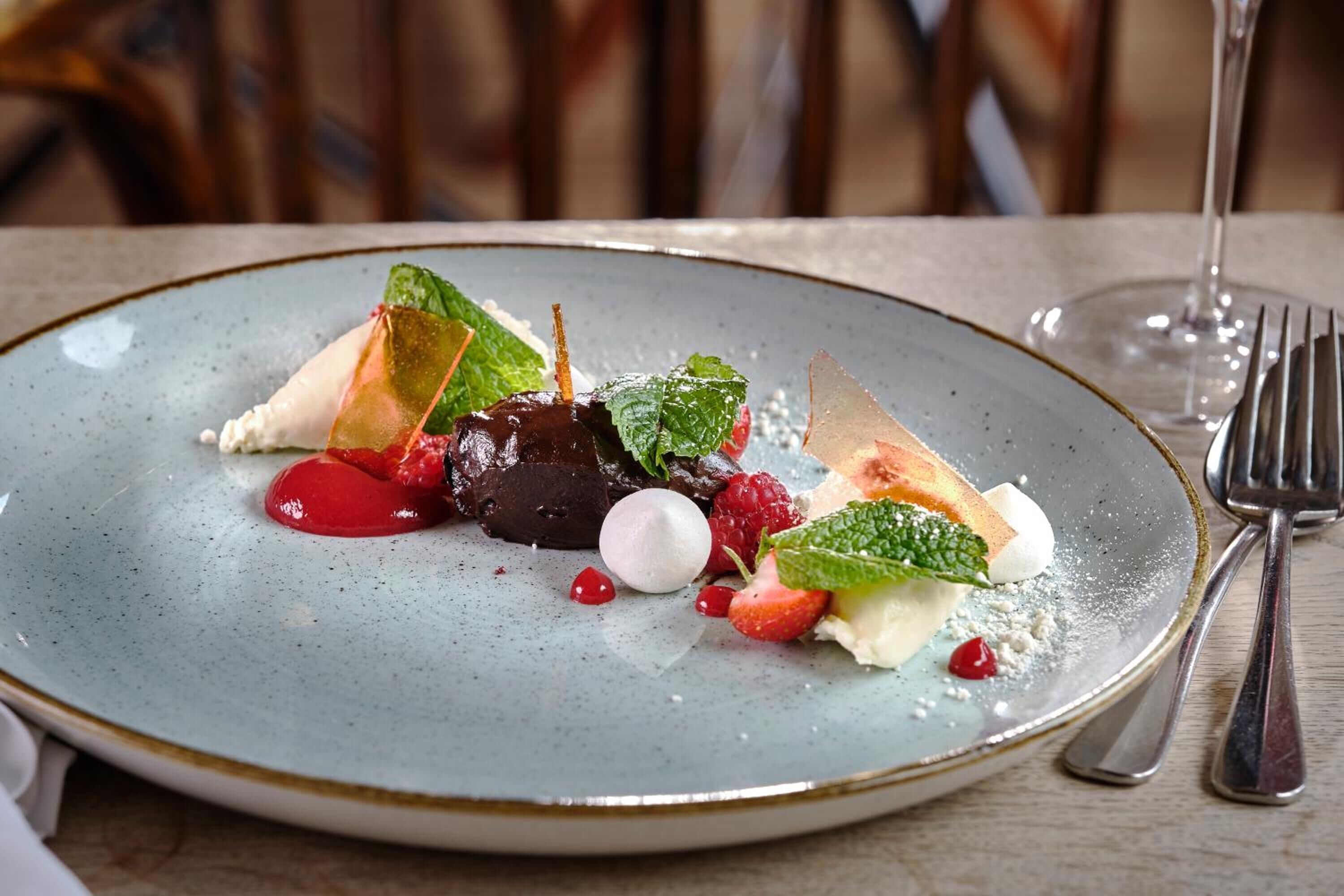 Un plato de postre con diversas frutas y una copa de vino.