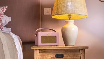 A wooden bedside table with a lamp and a vintage radio.