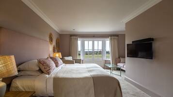A bedroom with a large bed, a TV mounted on the wall, and a view of the outdoors through the window.