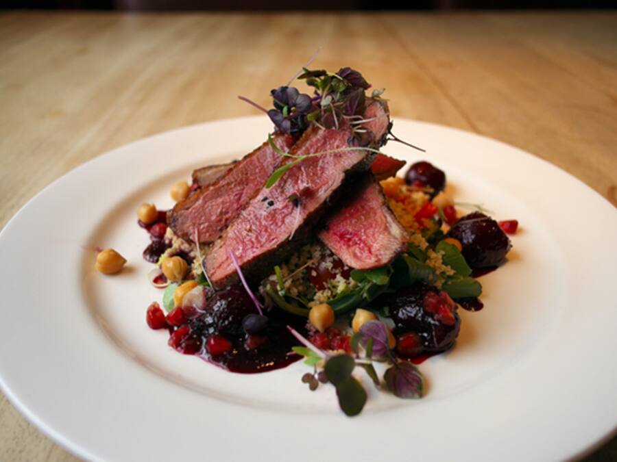 A white plate with a steak, greens, and chickpeas.