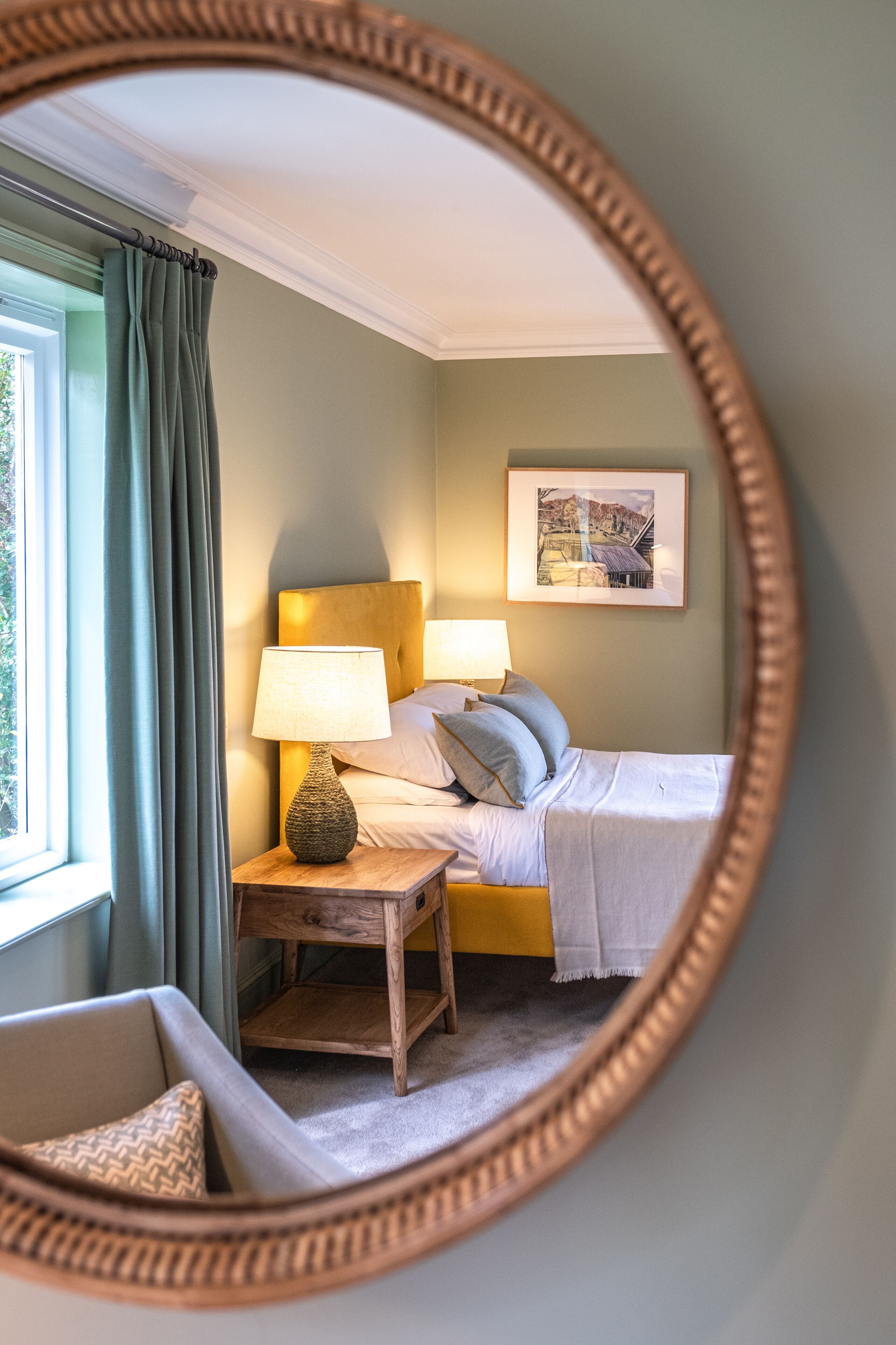 A bedroom with a bed, bedside table, lamp, and a framed picture on the wall.