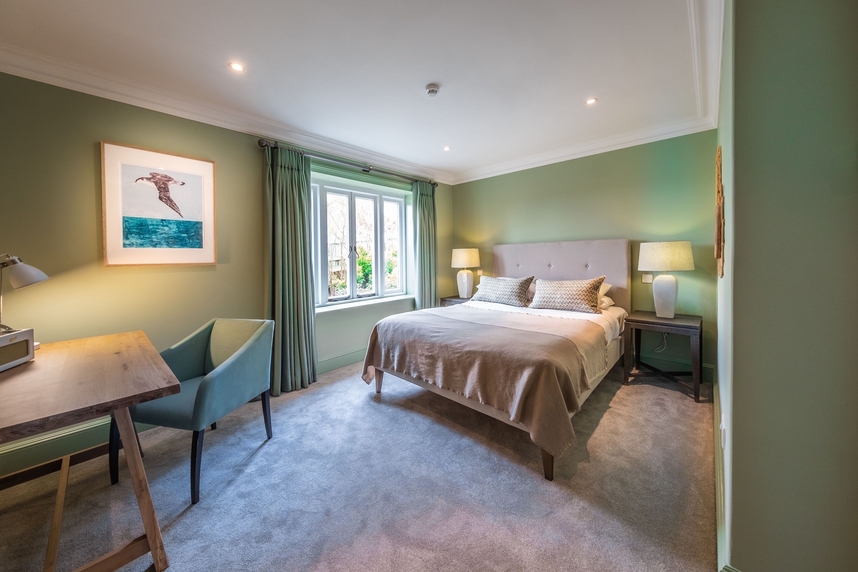 Une chambre à coucher avec un lit, des tables de chevet, un bureau et une chaise.