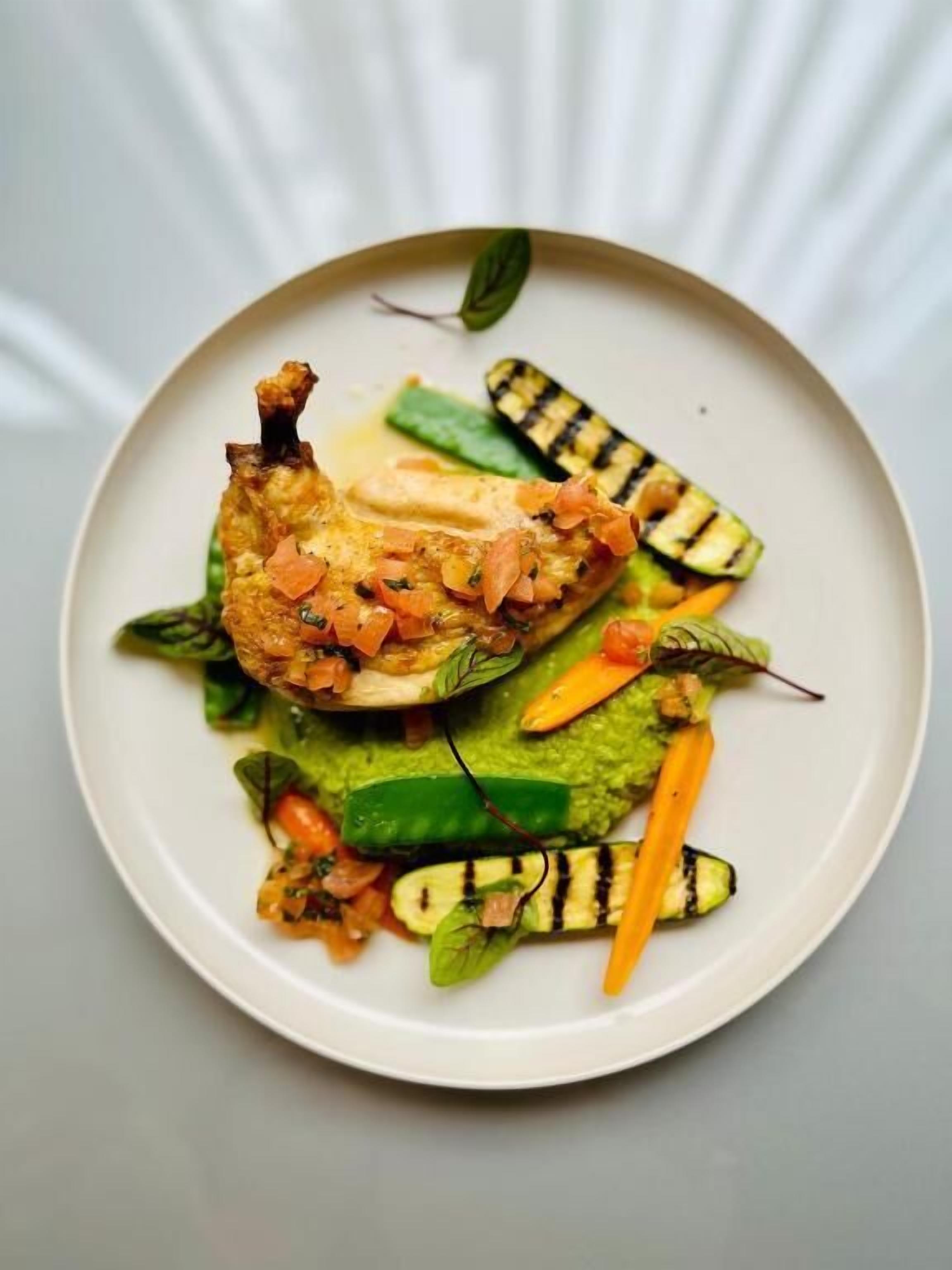 Un plato de comida con verduras a la parrilla y un trozo de pollo.