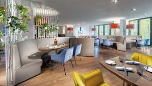 Un comedor moderno con una mesa de madera, sillas azules y amarillas, y un sofá blanco.