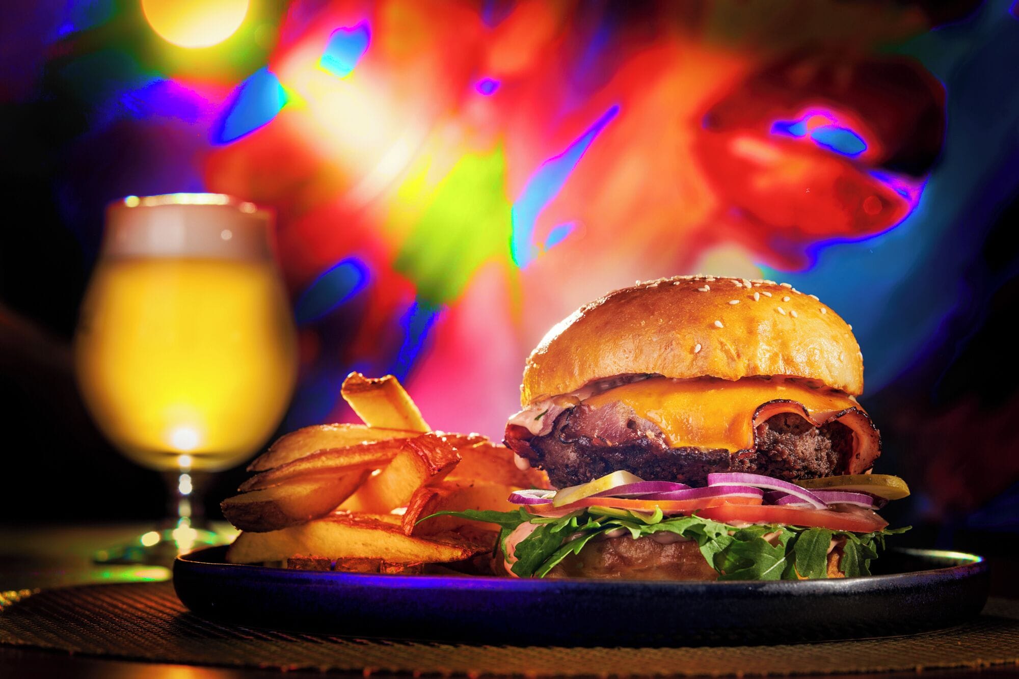 A burger with fries and a glass of beer on a table.