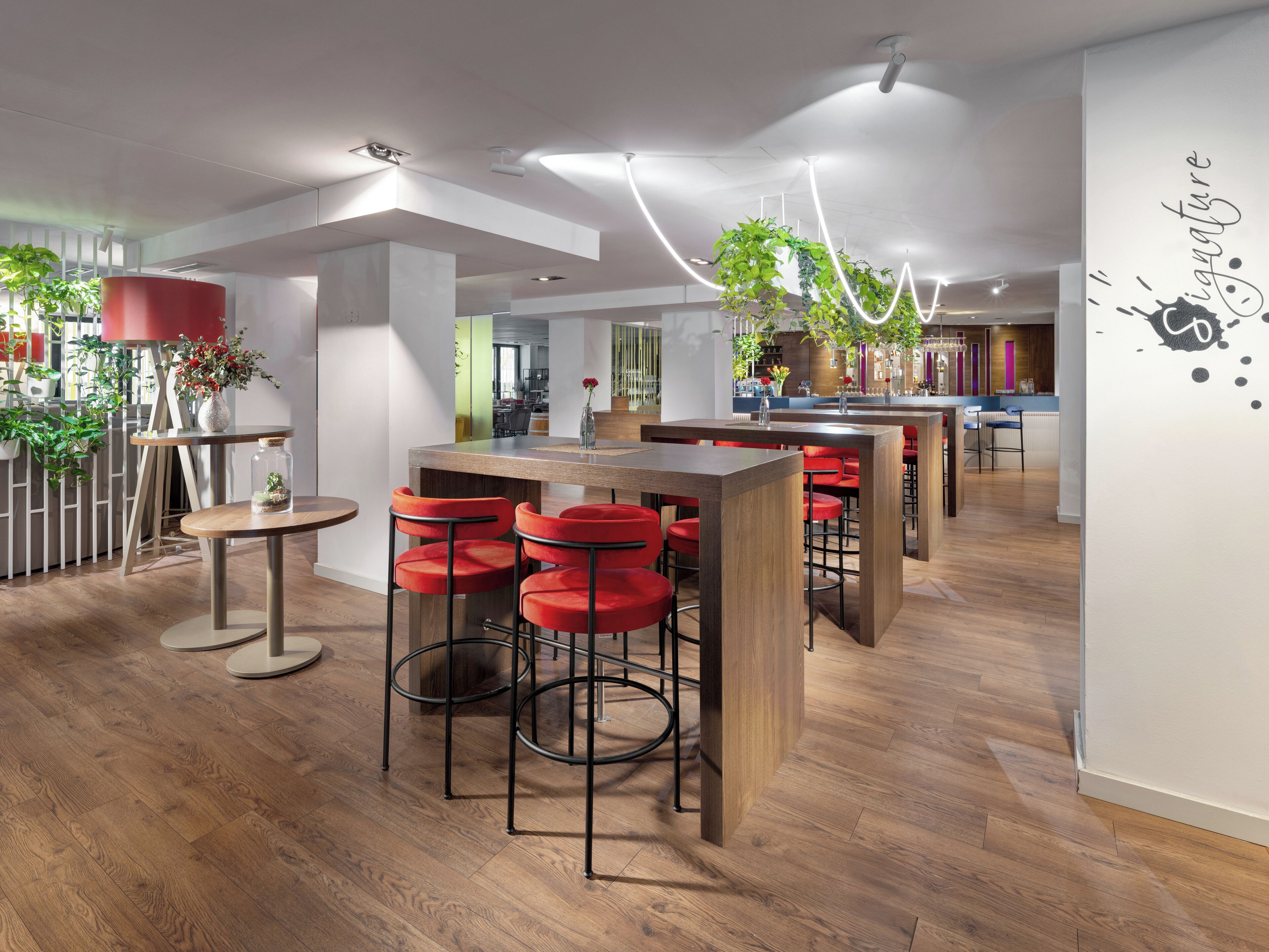 Um interior moderno com piso de madeira, banquetas vermelhas e um espaço de bar central.