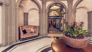 A lobby with a patterned sofa, a large potted plant, and a marble floor. - The Grand, York (York)