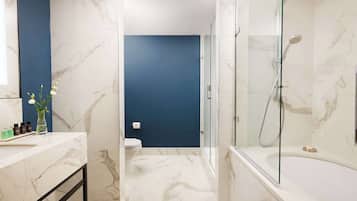 A modern bathroom with marble flooring, a glass-enclosed shower, and a blue accent wall.