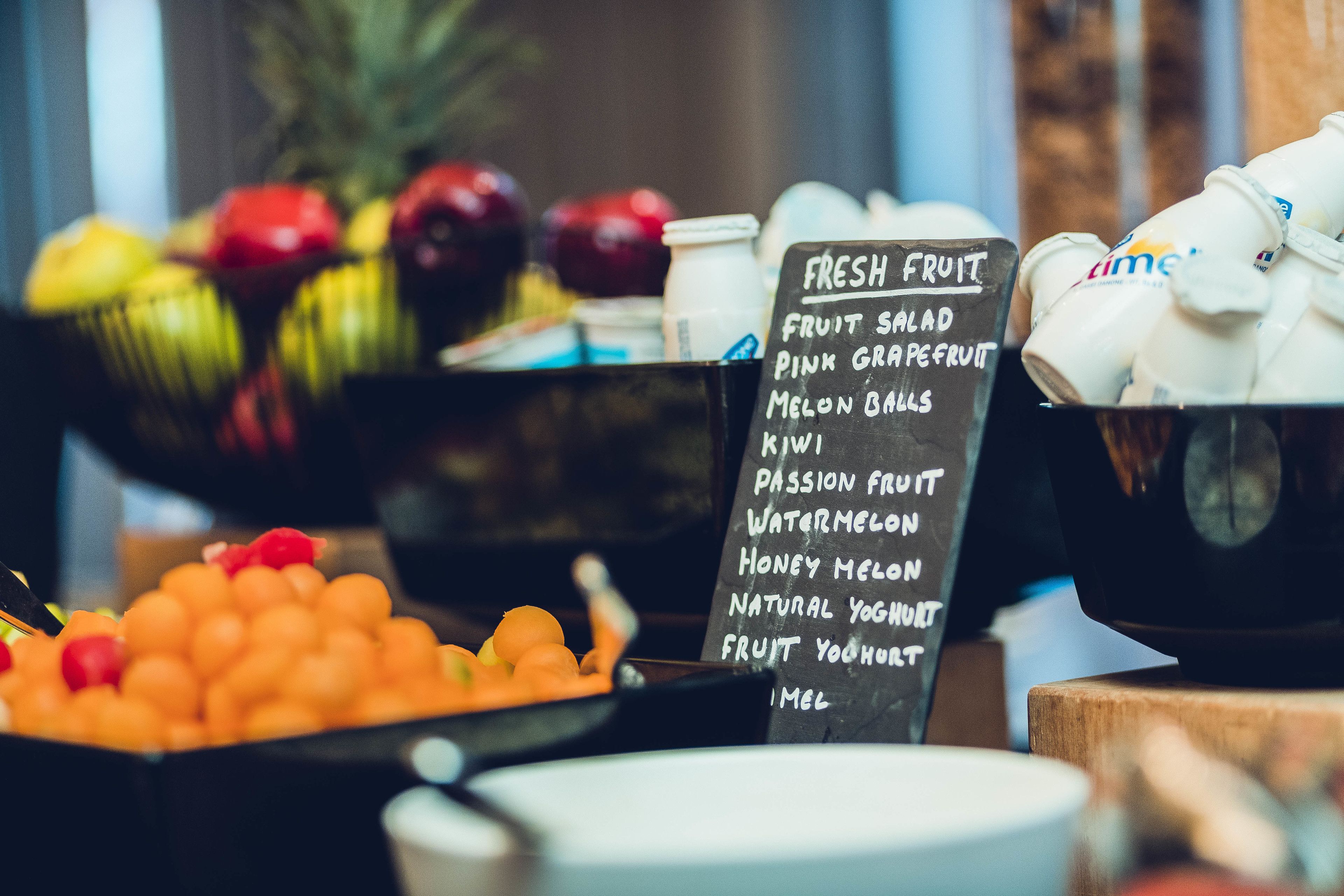 A fruit display with a sign listing items like fruit salad, pink grapefruit, and melon balls.