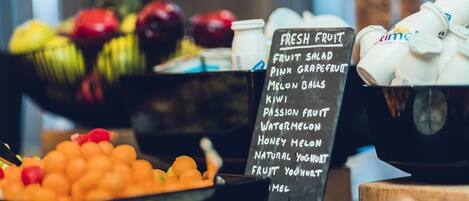 A fruit display with a sign listing items like fruit salad, pink grapefruit, and melon balls.