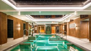 A modern indoor swimming pool with a central spiral sculpture, surrounded by wooden walls and a glass ceiling. - The Grand, York (York)