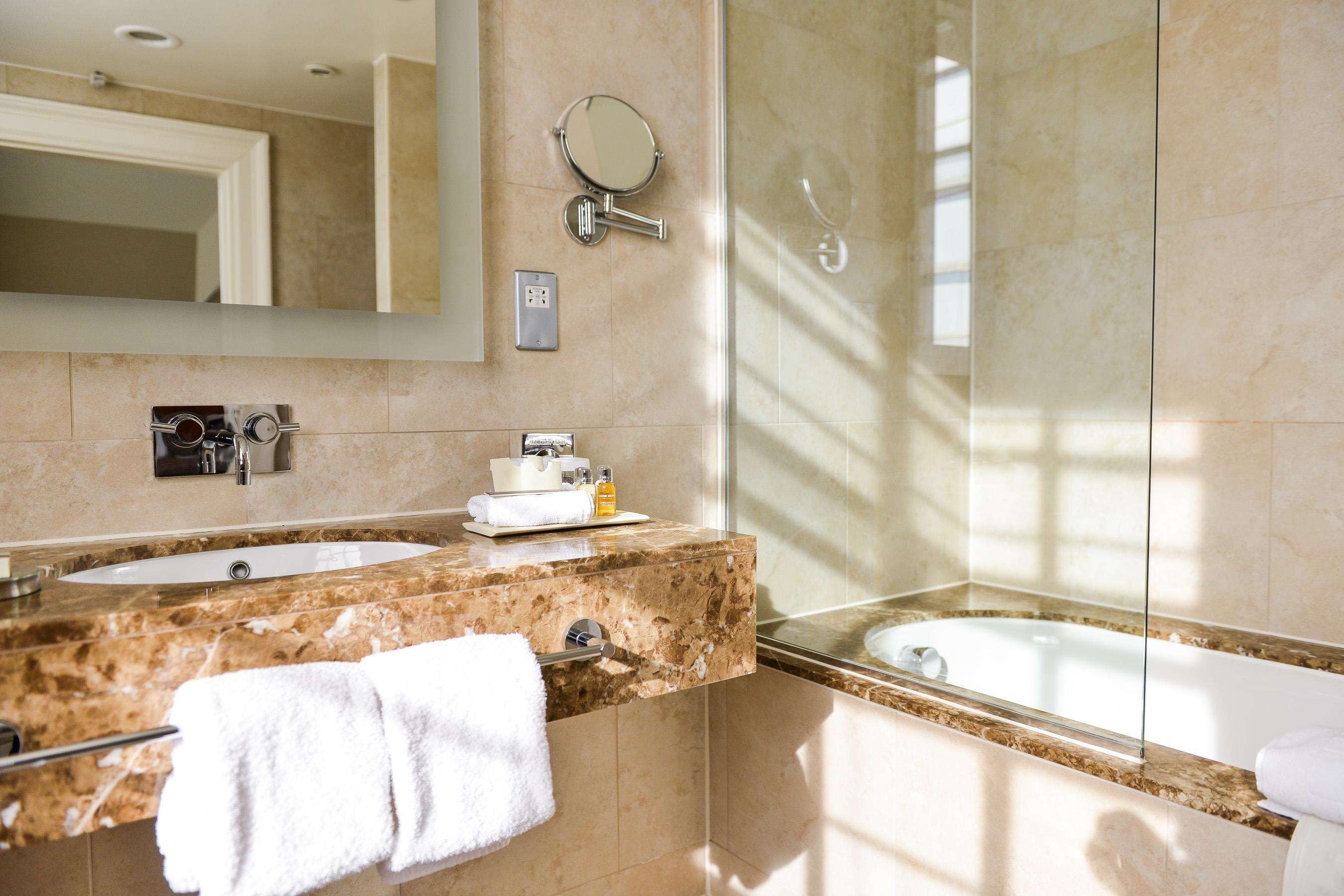 A modern bathroom with two sinks, a large mirror, a towel rack, and a shower.