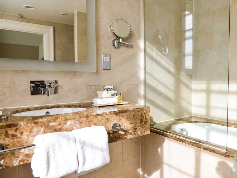 A modern bathroom with two sinks, a large mirror, a towel rack, and a shower.