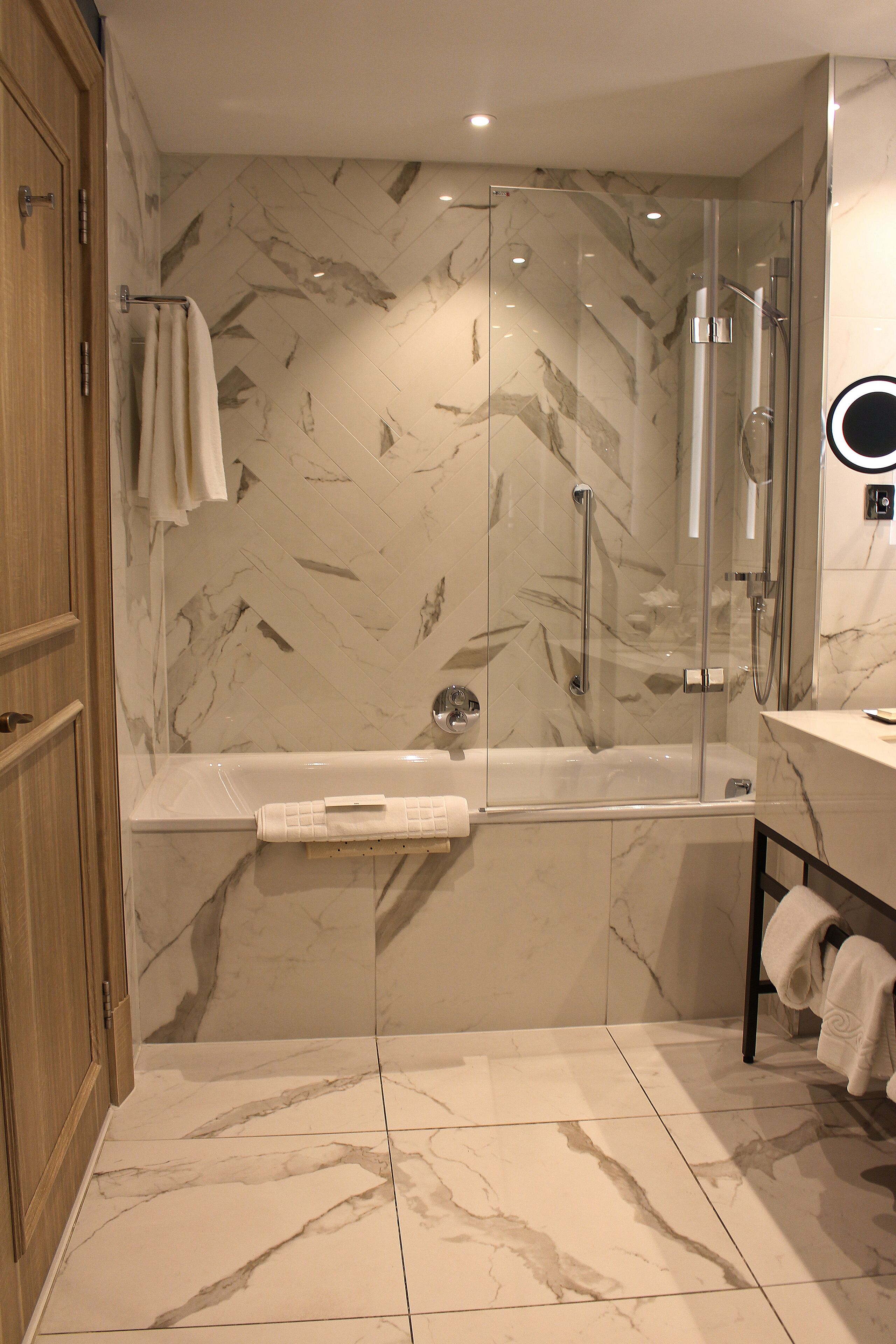 A modern bathroom with a glass-enclosed shower, a bathtub, and a vanity with a mirror.