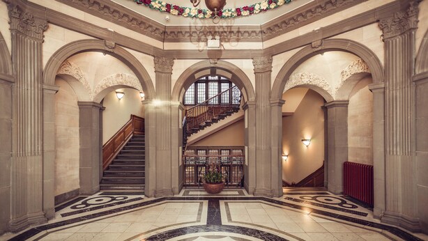 A grand lobby with a marble floor, a staircase, and ornate columns. - The Grand, York (York)