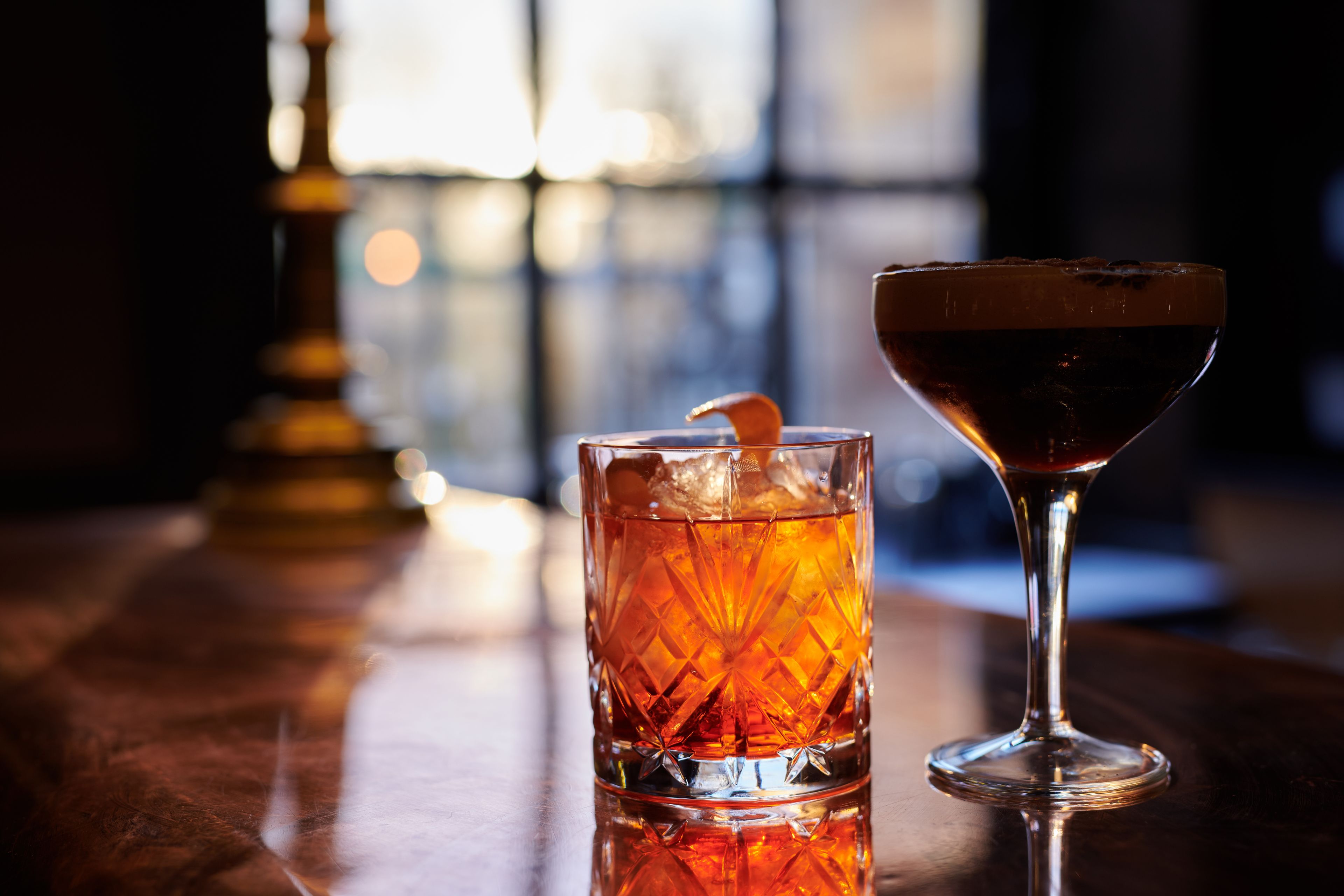 A bar setting with a glass and a martini glass on a wooden surface.