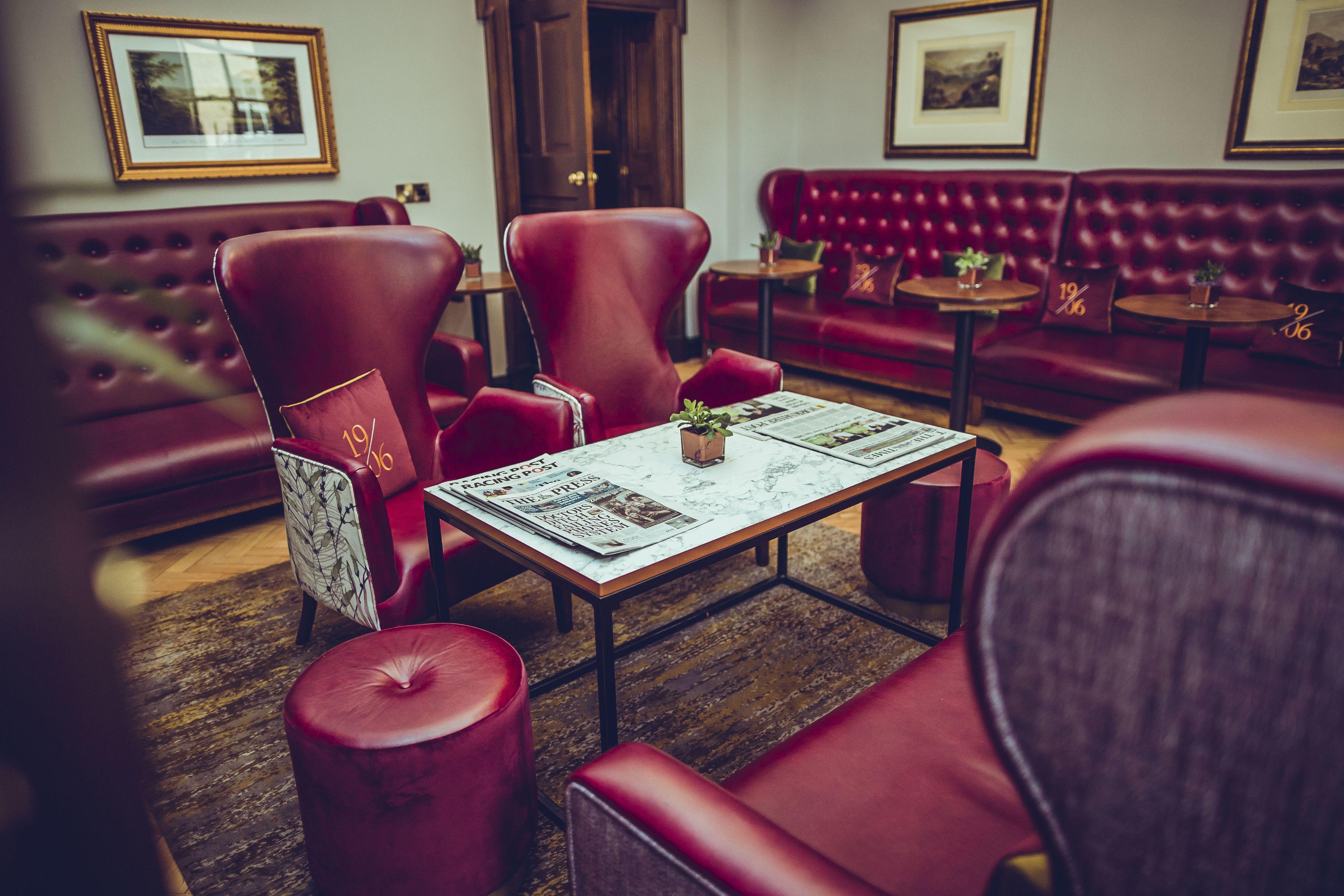 A red leather sofa, a red armchair, and a small table with a newspaper.