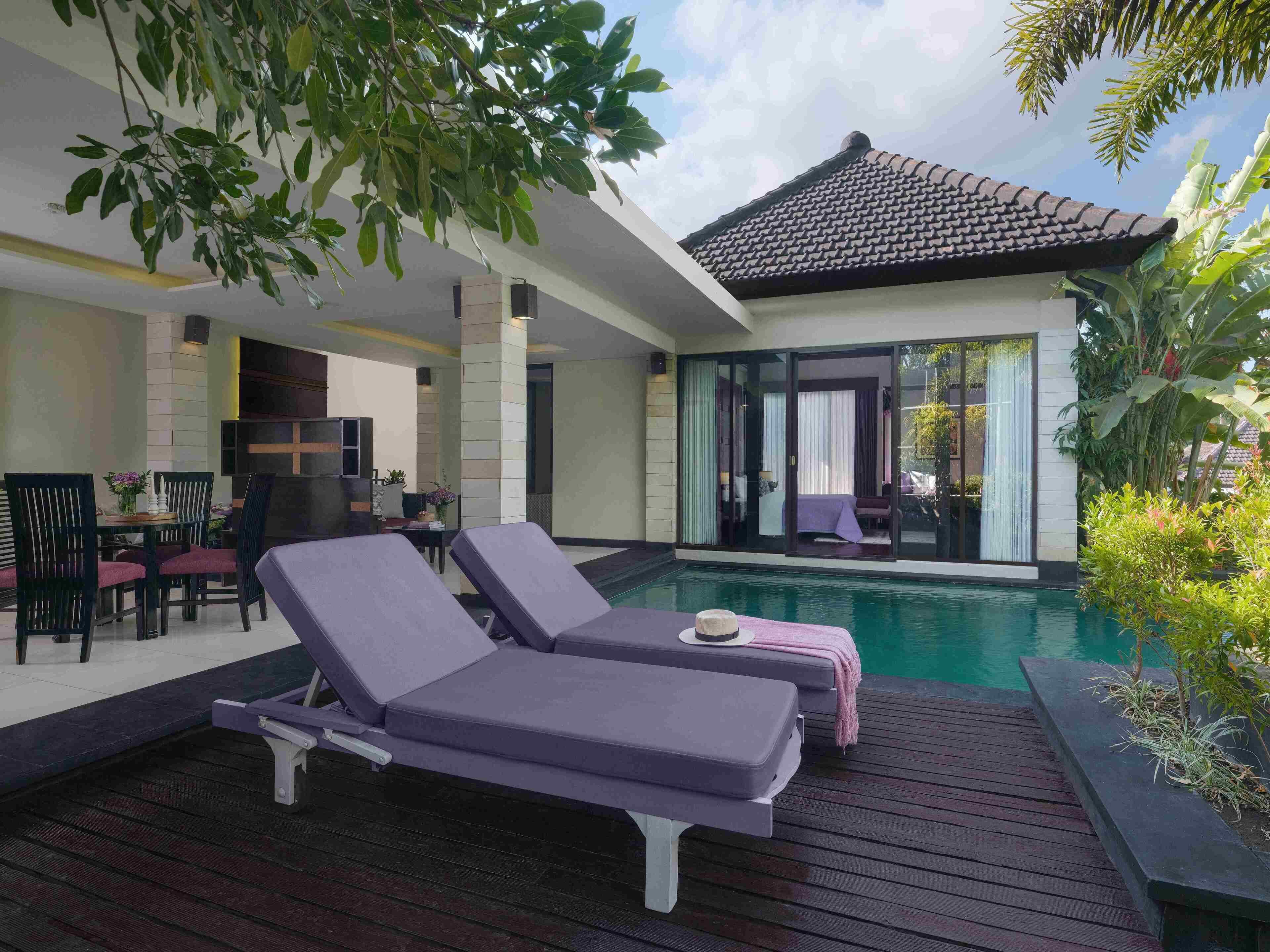 A modern outdoor pool area with lounge chairs, a dining setup, and a covered patio.