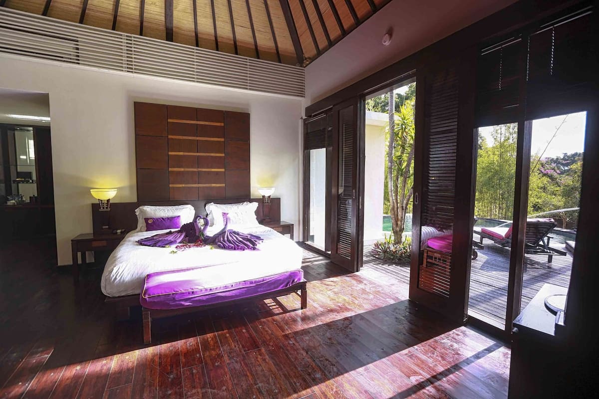Une chambre spacieuse avec un grand lit, un plancher en bois et une vue sur l’espace extérieur.
