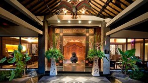 Una entrada tradicional con un arco decorativo, una estatua de piedra y plantas en macetas.
