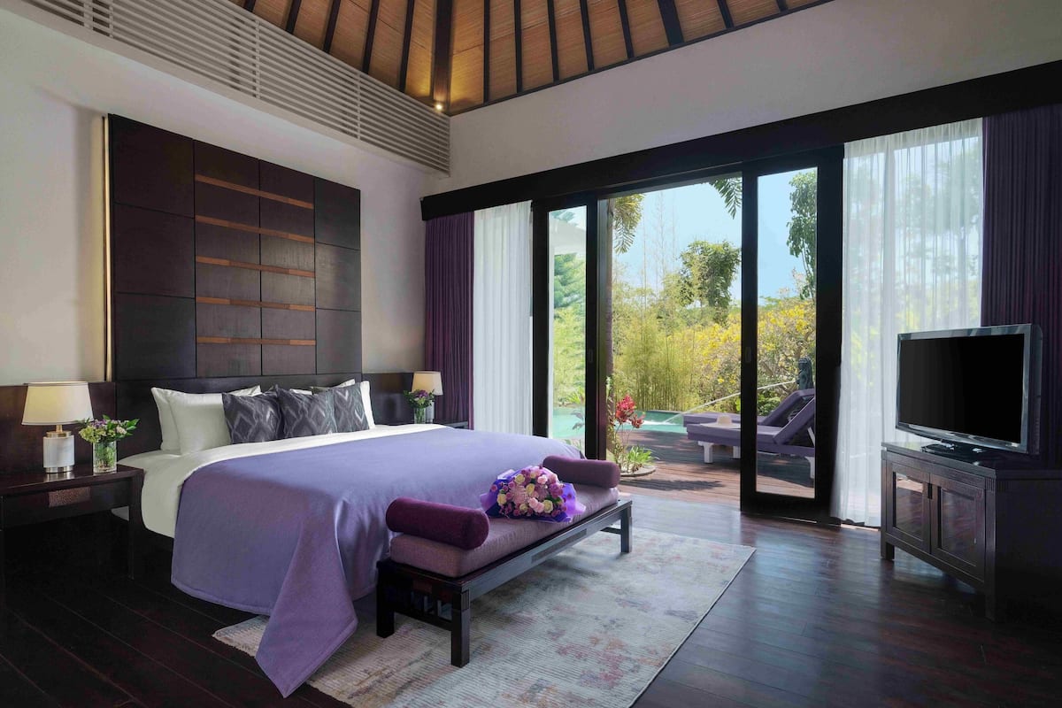 Une chambre moderne avec un grand lit, un banc, une télévision et une vue sur une piscine et un jardin.