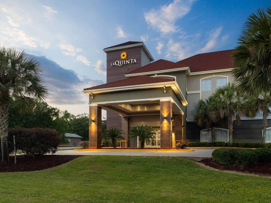 A hotel with a prominent entrance, palm trees, and a clear sky.