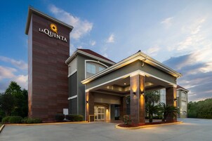 Un hotel con un llamativo letrero de 'La Quinta', un acceso cubierto y un jardín delantero cuidado.