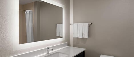 A bathroom with a white sink, a mirror, a towel rack, and a toilet.