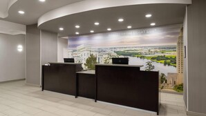 Balcão de recepção com um mural da paisagem urbana ao fundo, teto curvo com iluminação embutida e design moderno e clean.