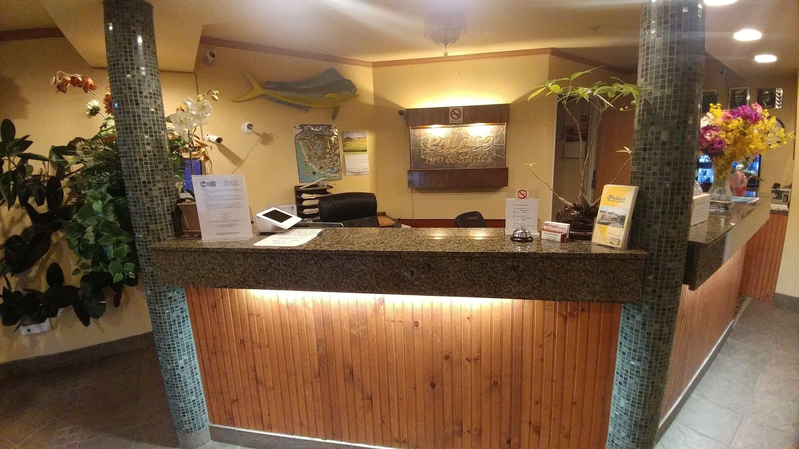 A reception desk with a wooden panel design, a digital screen, and a sign indicating a no-smoking policy.
