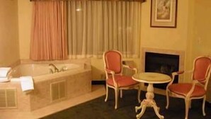 Ein Zimmer mit einer Badewanne, zwei Stühlen, einem kleinen Tisch und einem Kamin.