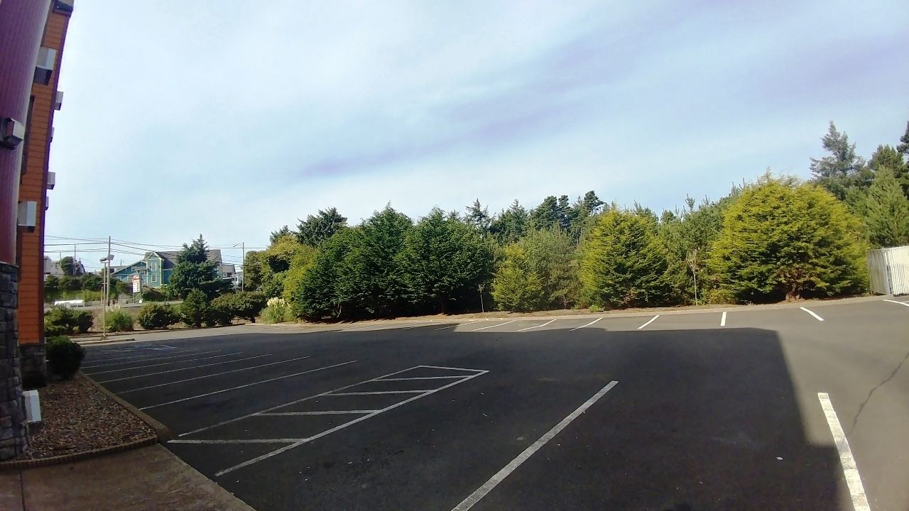 Un parking avec des places délimitées et un bâtiment situé sur la gauche.