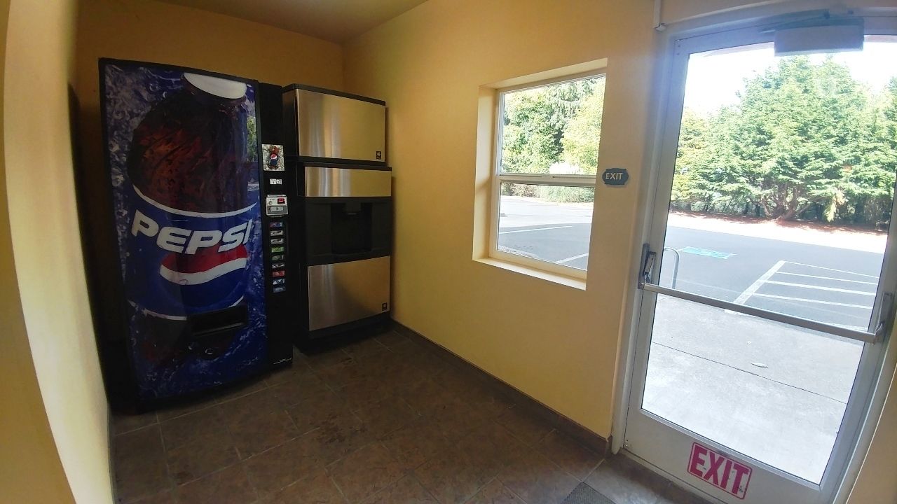 A hallway with a Pepsi vending machine, a window, and an exit door leading outside.