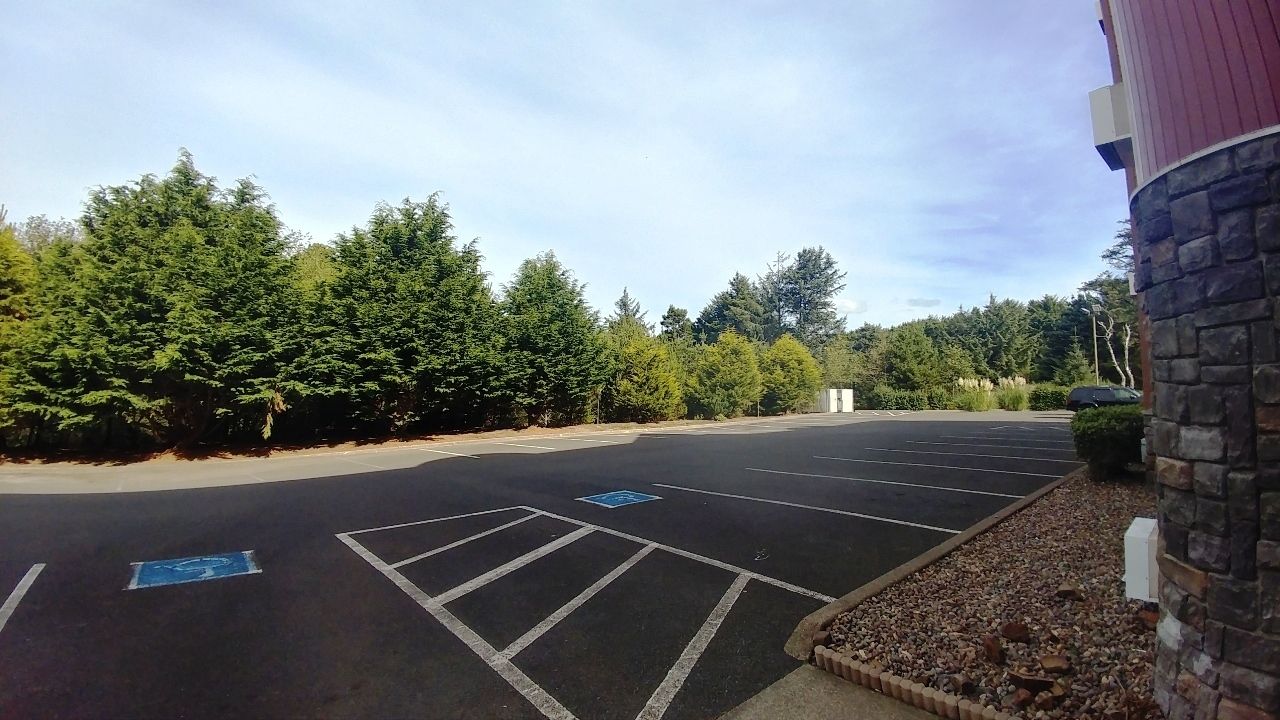A parking lot with marked spaces, including a handicapped parking space, and a building with a stone facade.