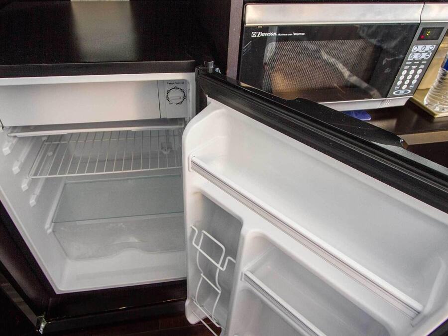 Un refrigerador abierto con un microondas encima.