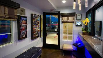 A hotel lobby with a reception desk, seating area, and a view of the street outside.