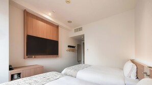A hotel room with two beds, a TV mounted on the wall, a small desk with a coffee machine, and a wardrobe. - Vessel Inn Hakata Nakasu (Fukuoka)