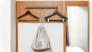 A room with a wooden wardrobe, a hanging clothes rack, and a bag labeled "ROOM WEAR" hanging from the rack. - Vessel Inn Hakata Nakasu (Fukuoka)