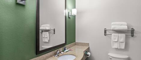A bathroom with a granite countertop sink, a large mirror, a toilet, and a towel rack.