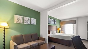 Ein Hotelzimmer mit grüner Wand, einer Couch, einem Bett, einer Lampe und gerahmten Bildern.