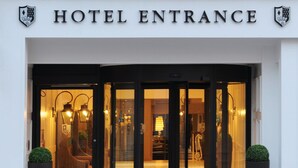 A hotel entrance with a revolving door, a reception desk, and two potted plants. - Macdonald Windsor Hotel (Windsor)
