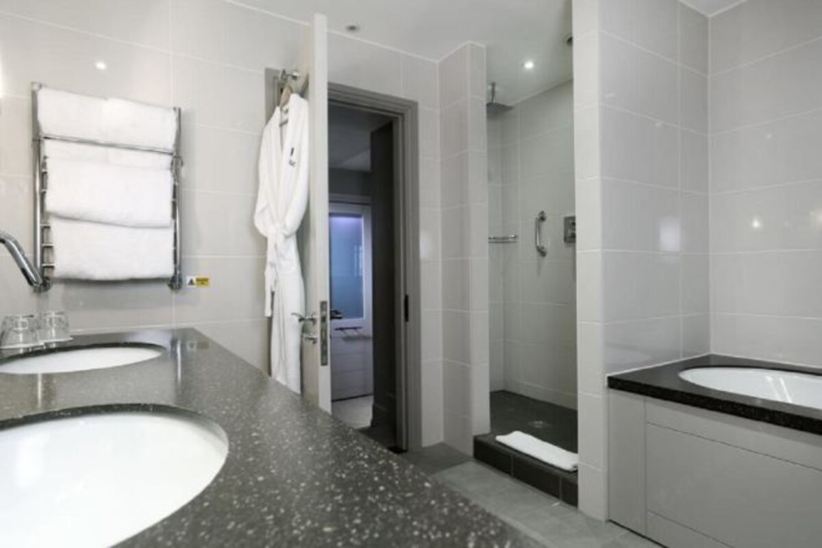 Un baño moderno con dos lavamanos y una ducha a pie.