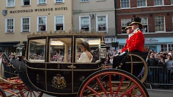 A carriage with a black and gold exterior, a driver, and a passenger.